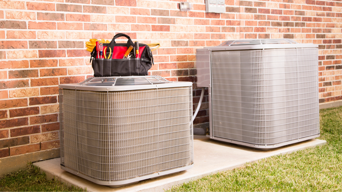 Outdoor AC units beside brick home help homeowners choose efficient cooling equipment size and type.
