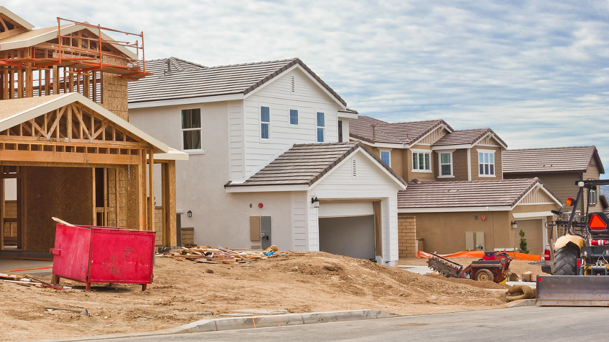 Three new construction houses side-by-side, with different levels of completion.