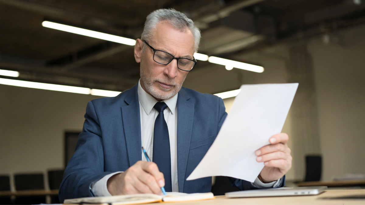 Attorney reviewing documents helps divide real estate assets during high-asset divorce settlement negotiations carefully and fairly.