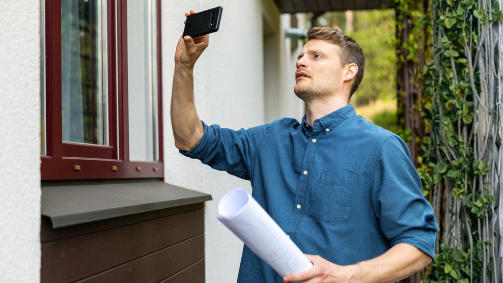 Landlord photographing exterior window during proactive property assessment to protect long-term rental property investment value.