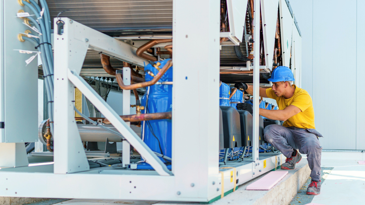 Technician inspecting commercial refrigeration equipment helps property managers prevent failures, downtime, and costly tenant disruptions.