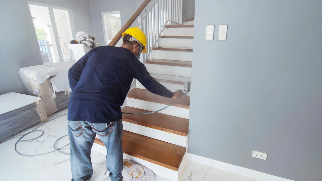 Contractor painting staircase during rental property renovation turnover helping investors streamline updates and prepare units.