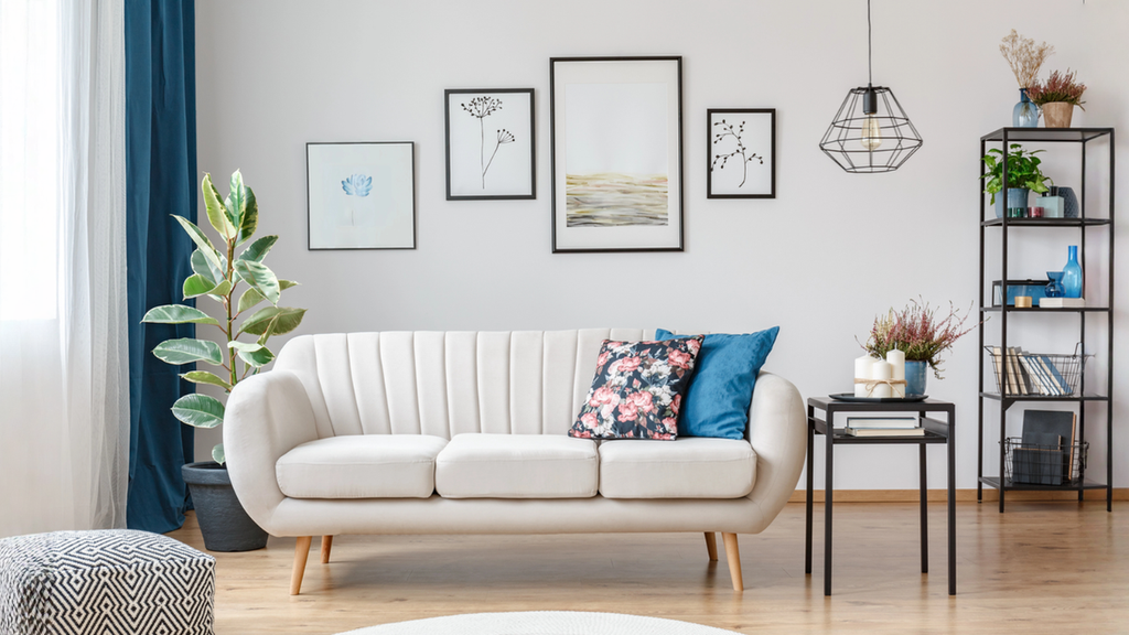 Bright living room designed around natural light with white sofa, blue curtains, plants, and decor.