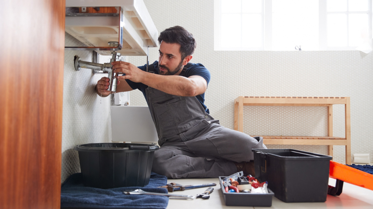 Plumber inspecting sink pipes to identify persistent plumbing problems, hidden leaks, blockages, and repair sources.