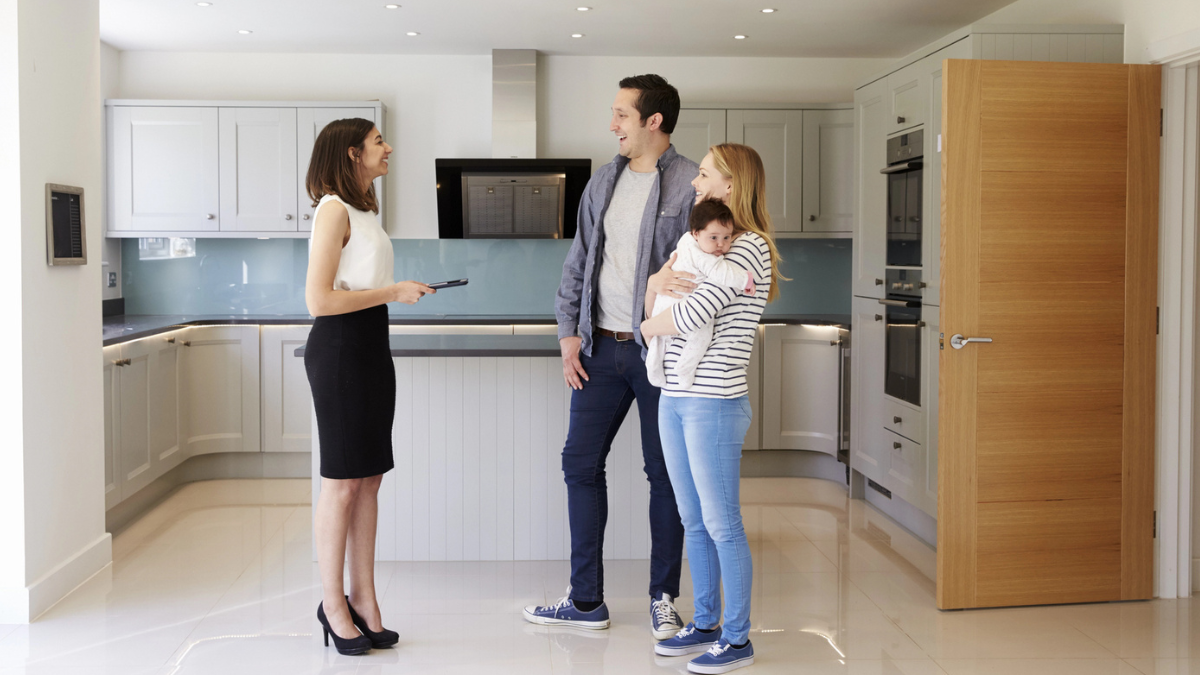 Real estate agent showing home to buyers helping sellers maximize profit through presentation and pricing.