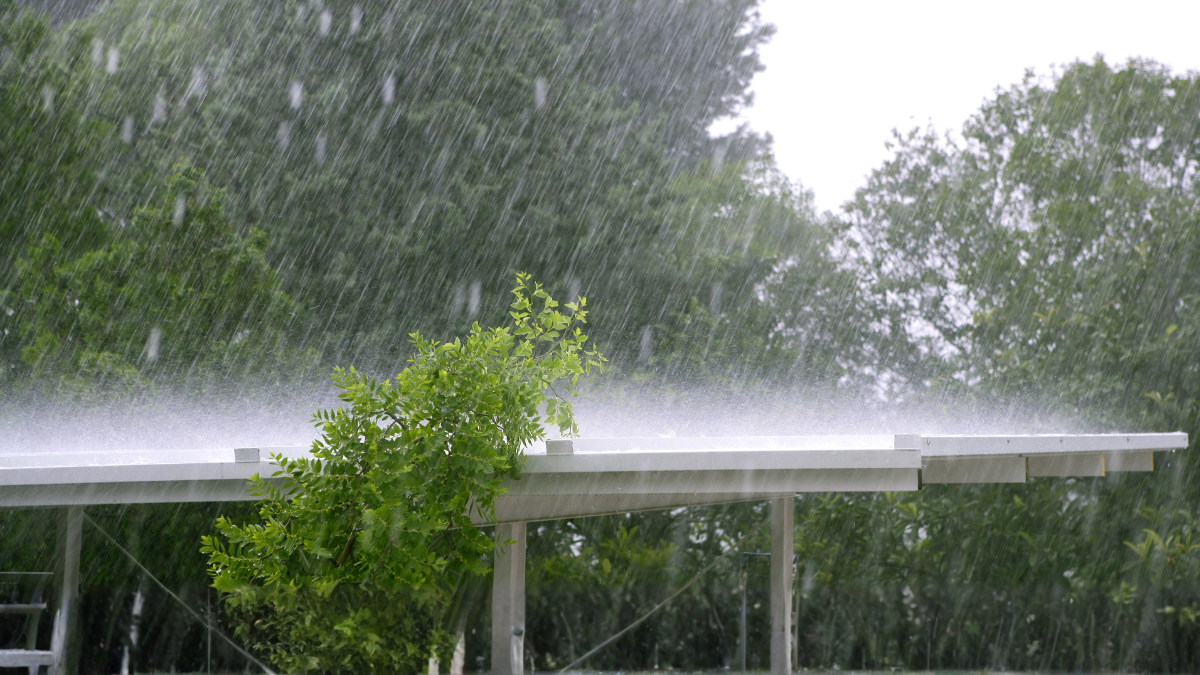 Heavy rain pouring down on a rental property roof during a storm