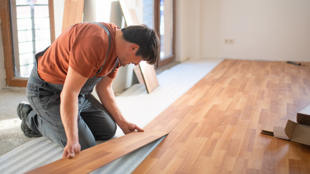 Contractor installing durable flooring during rental property renovation designed to attract and retain long-term tenants.