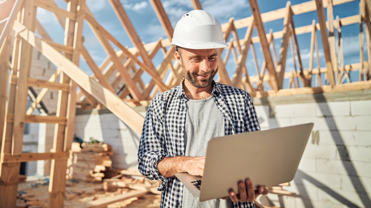 New construction company contractor uses laptop on jobsite to prepare competitive house build bids.