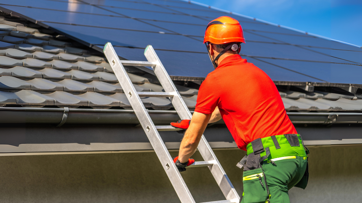 Man on ladder climbing onto roof for inspection