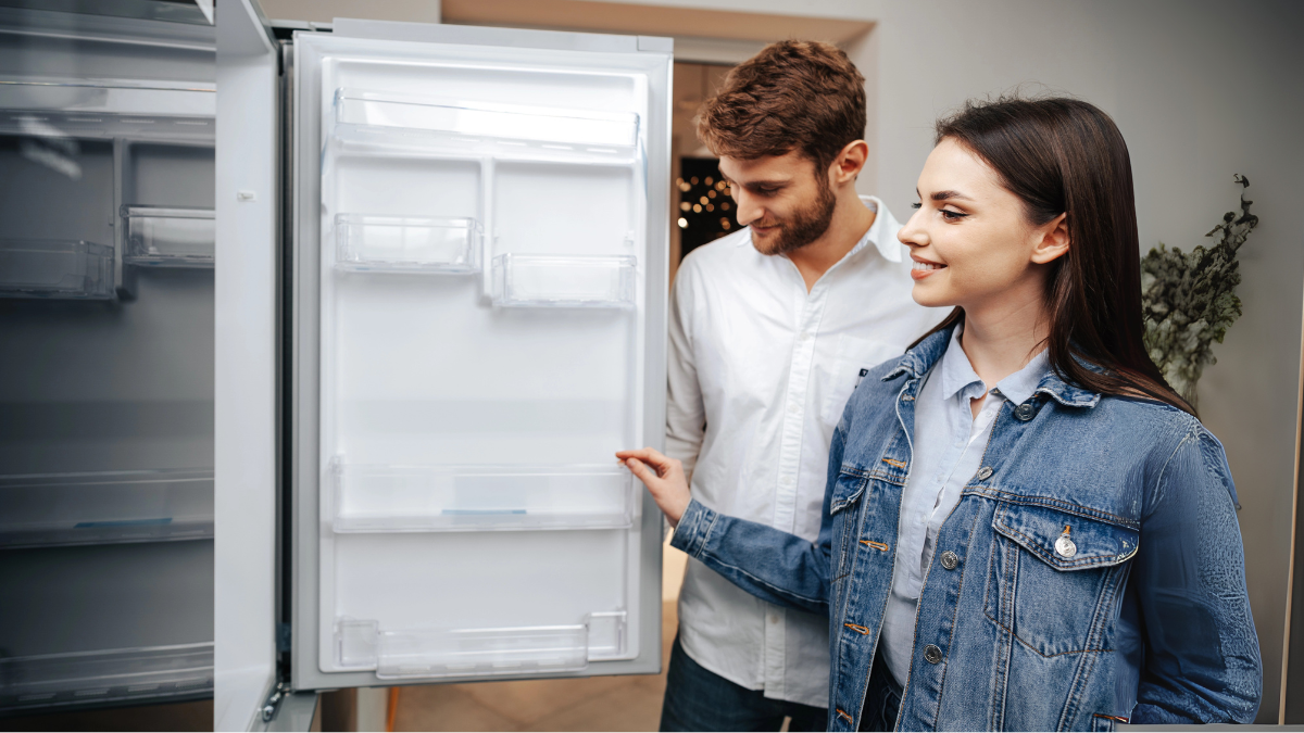 Couple looking at refrigerator appliance in rental unit