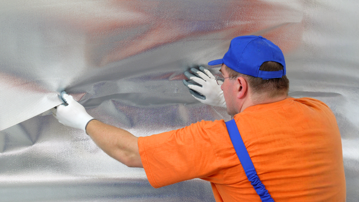 Contractor installing attic radiant barrier helps reduce heat transfer, improve energy efficiency, and lower cooling costs.
