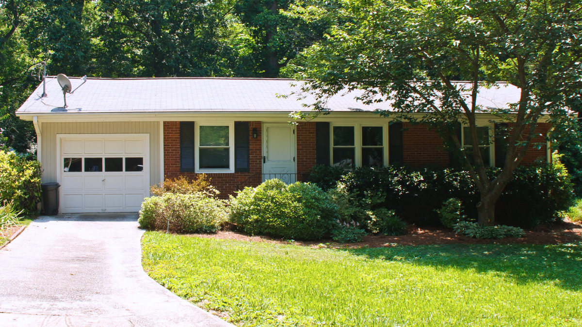 Single-story home exterior with lawn, trees, garage, and essential overlooked maintenance tasks homeowners often forget.