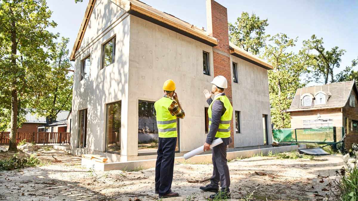 Contractors reviewing home construction site showing importance of hiring quality builder for successful residential project.