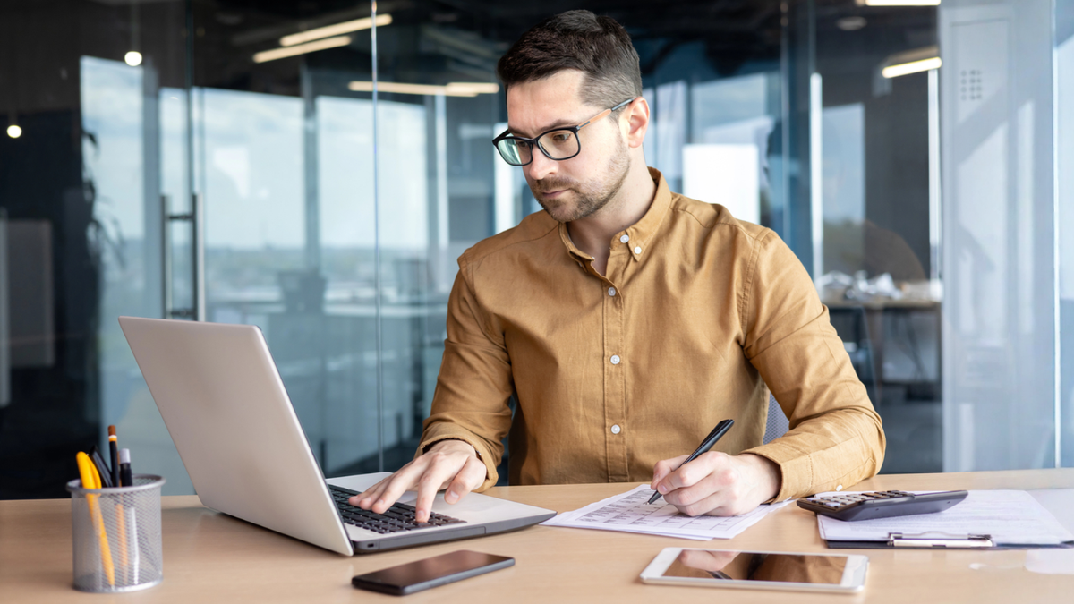 Investor analyzing property numbers on laptop to evaluate rental investment returns, cash flow, and expenses.
