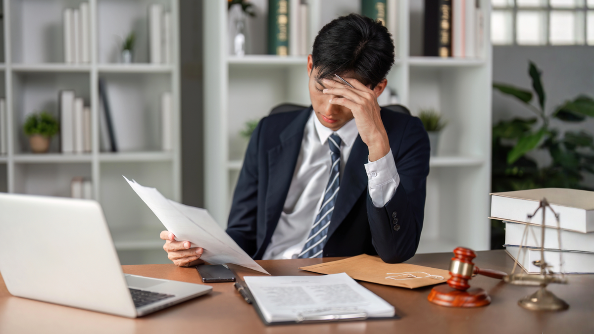Frustrated lawyer reviewing property title documents with issues.