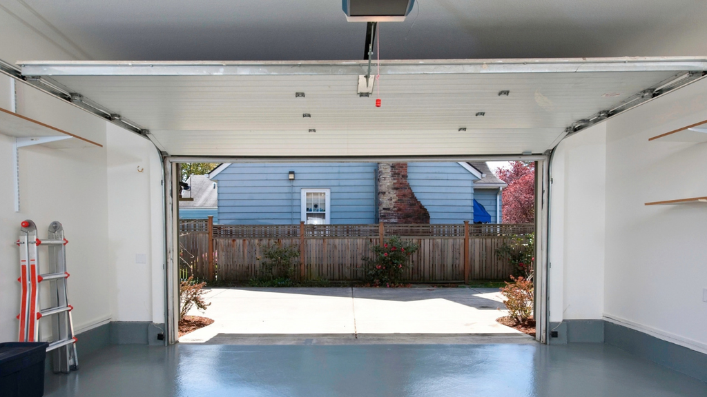 Open residential garage door shows replacement cost factors including size, materials, hardware, opener, and installation.