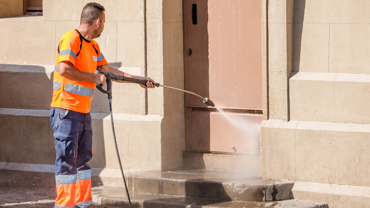 Man power washing commercial building