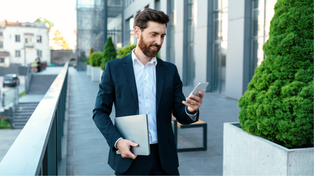 Property manager using smartphone outside apartment building handling tenant communication, maintenance, and daily rental operations.