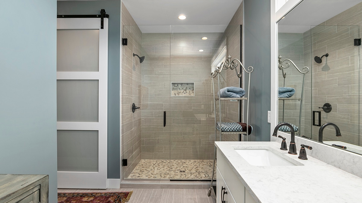 Modern designer bathroom with glass shower, tile accents, and sleek finishes showcasing stylish home design.